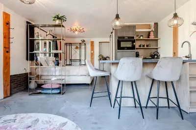 a kitchen with two white bar stools and a counter at Bed and Beach Zandvoort in Zandvoort