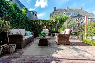 a patio with wicker chairs and a couch and a table at Bed and Beach Zandvoort in Zandvoort