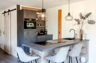 a kitchen with a large island with white chairs at Bed and Beach Zandvoort in Zandvoort