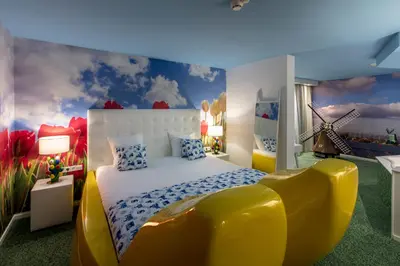 a bedroom with a large bed and a yellow chair at Hotel Mitland in Utrecht