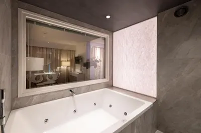 a bath tub in a bathroom with a large mirror at Hotel Mitland in Utrecht