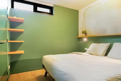 a bedroom with a bed and a green wall at Waterlinie Lodges in Utrecht