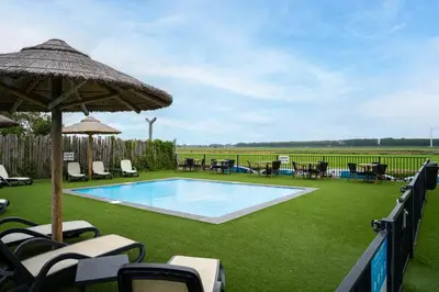 a swimming pool with chairs and an umbrella at Park Westerkogge in Berkhout