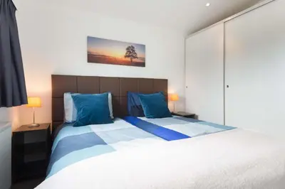 a bedroom with a large bed with blue pillows at Park Westerkogge in Berkhout
