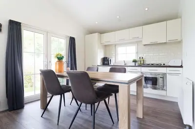 a kitchen with a wooden table and chairs at Park Westerkogge in Berkhout