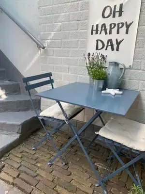 a blue table with a chair and a sign that says oil happy day at Appartement 't Souterrain in Zandvoort