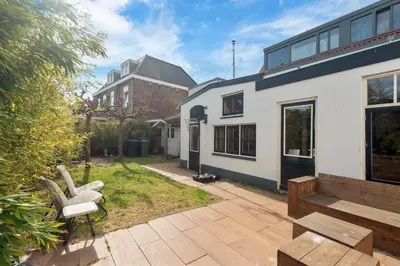 a backyard with a bench and a house at Second Paradise for 2 adults and 2 children in Zandvoort