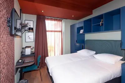 a bedroom with a bed and a desk with a computer at Hotel Nicolaas Witsen in Amsterdam