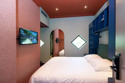 a bedroom with a bed and a tv on a wall at Hotel Nicolaas Witsen in Amsterdam