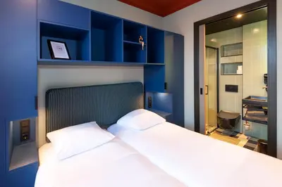 a bedroom with blue walls and a bed with white pillows at Hotel Nicolaas Witsen in Amsterdam