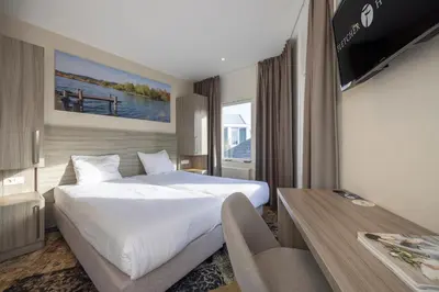 a hotel room with a large bed and a television at Fletcher Hotel - Resort Spaarnwoude in Velsen-Zuid