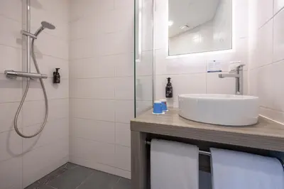 a white bathroom with a sink and a shower at Fletcher Hotel - Resort Spaarnwoude in Velsen-Zuid