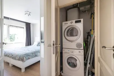 a laundry room with a washer and dryer next to a bed at Luxury Apartment near Utrecht & Amsterdam in Breukelen