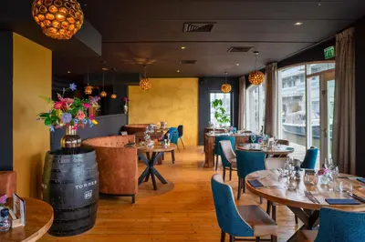 a restaurant with tables and chairs and a barrel at Luxury Apartment near Utrecht & Amsterdam in Breukelen