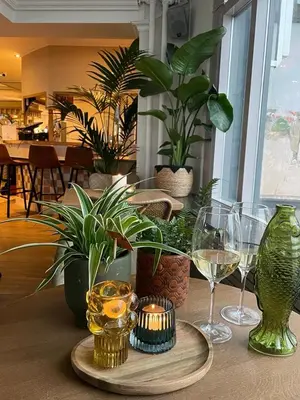 a table with glasses of wine and plants on it at Hotel Noordzee in Katwijk