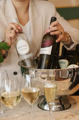 a woman holding a bottle of wine in a bowl of wine glasses at Hotel Noordzee in Katwijk