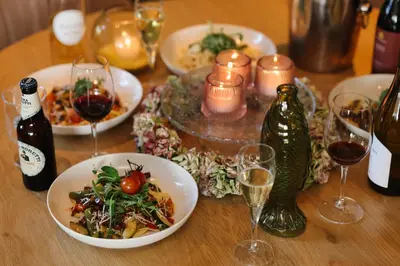 a wooden table with plates of food and wine glasses at Hotel Noordzee in Katwijk