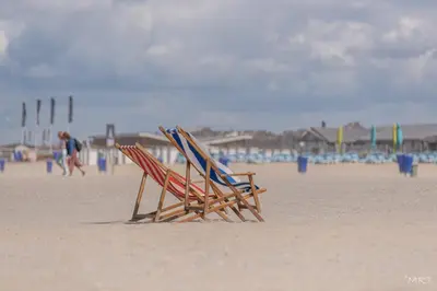two beach chairs sitting on the sand at the beach at Hotel Noordzee in Katwijk