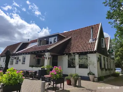 a building with tables and flowers in front of it at 't Wapen van Middelie in Middelie