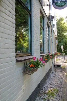 a building with a window with baskets of flowers on it at 't Wapen van Middelie in Middelie