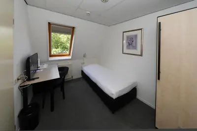 a bedroom with a bed and a desk with a computer at Golden Tulip Ampt van Nijkerk in Nijkerk