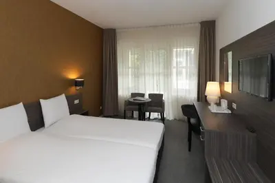 a hotel room with a bed and a desk at Golden Tulip Ampt van Nijkerk in Nijkerk