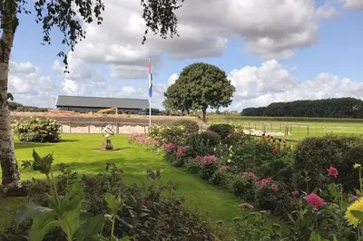 a garden with flowers and a flag in the background at De Mast bij Fort Vechten on the countryside & close to Utrecht in Bunnik