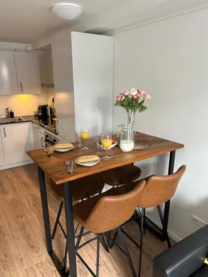 a kitchen with a wooden table with chairs and flowers at Noordwijk BB228 in Noordwijk