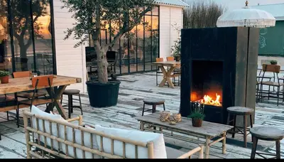 a fireplace in the middle of a patio with tables and chairs at Noordwijk BB228 in Noordwijk