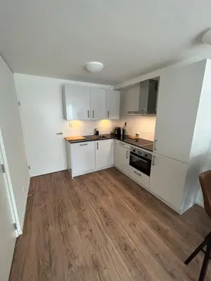 a kitchen with white cabinets and a wooden floor at Noordwijk BB228 in Noordwijk