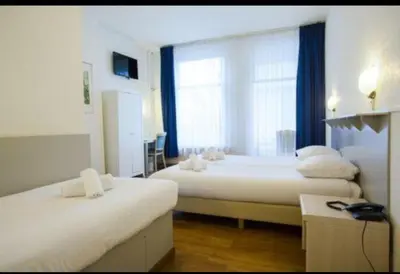 a hotel room with two beds and a window at Hotel Titus City Centre in Amsterdam