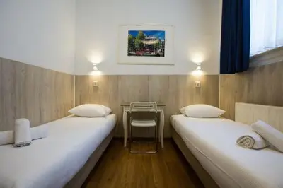 two beds in a small room with a table at Hotel Titus City Centre in Amsterdam