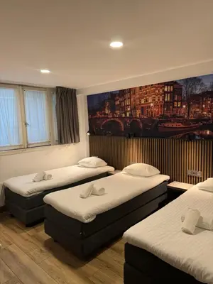 a room with three beds and a painting on the wall at Hotel Titus City Centre in Amsterdam