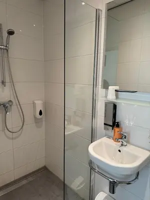 a white bathroom with a sink and a shower at Hotel Titus City Centre in Amsterdam