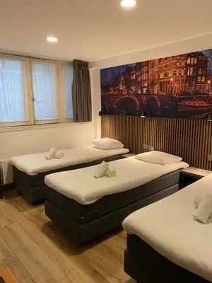 a room with three beds and a painting on the wall at Hotel Titus City Centre in Amsterdam