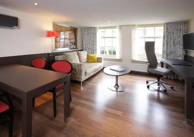 a living room with a couch and a table and chairs at Krasnapolsky Apartments in Amsterdam