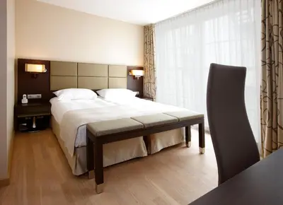 a hotel room with a large bed and a desk at Krasnapolsky Apartments in Amsterdam