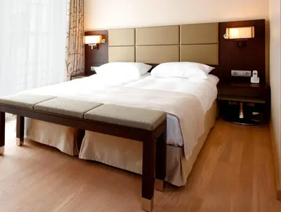 a bedroom with a large bed with a bench on it at Krasnapolsky Apartments in Amsterdam