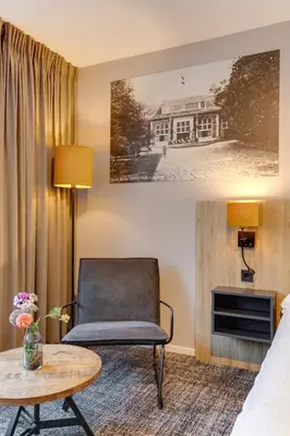 a hotel room with a chair and a table at Hotel Ernst Sillem Hoeve in Den Dolder