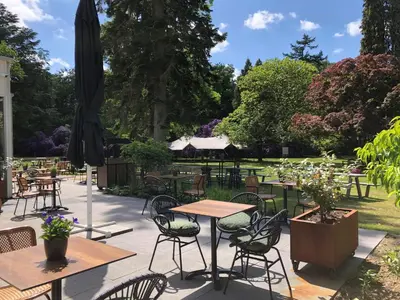 a patio with tables and chairs and an umbrella at Hotel Ernst Sillem Hoeve in Den Dolder