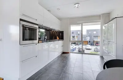 a kitchen with white cabinets and a large window at Cairo in Almere