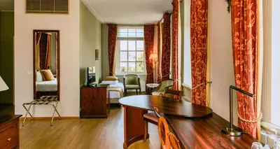a living room with a table and a bedroom at Grand Hotel Karel V in Utrecht