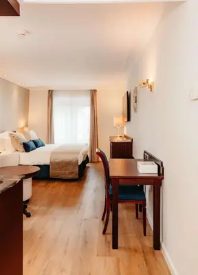 a hotel room with a bed and a desk and a bed at Grand Hotel Karel V in Utrecht