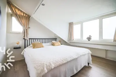 a bedroom with a bed with white sheets and windows at sunshine in Schoorl
