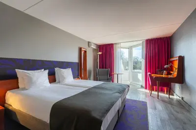 a hotel room with a large bed and a window at Amrâth Berghotel Amersfoort in Amersfoort