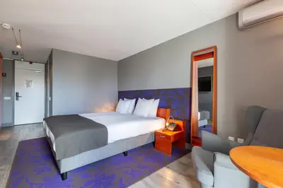a hotel room with a bed and a chair and a table at Amrâth Berghotel Amersfoort in Amersfoort