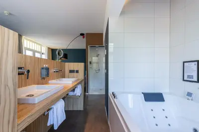 a bathroom with two sinks and a bath tub at Amrâth Berghotel Amersfoort in Amersfoort
