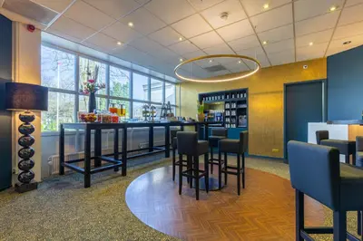 a bar with stools in a room with windows at Amrâth Berghotel Amersfoort in Amersfoort