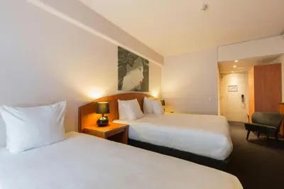 a hotel room with two beds and a chair at Leonardo Hotel Utrecht City Center in Utrecht