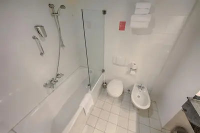 a white bathroom with a shower and a toilet at Leonardo Hotel Utrecht City Center in Utrecht